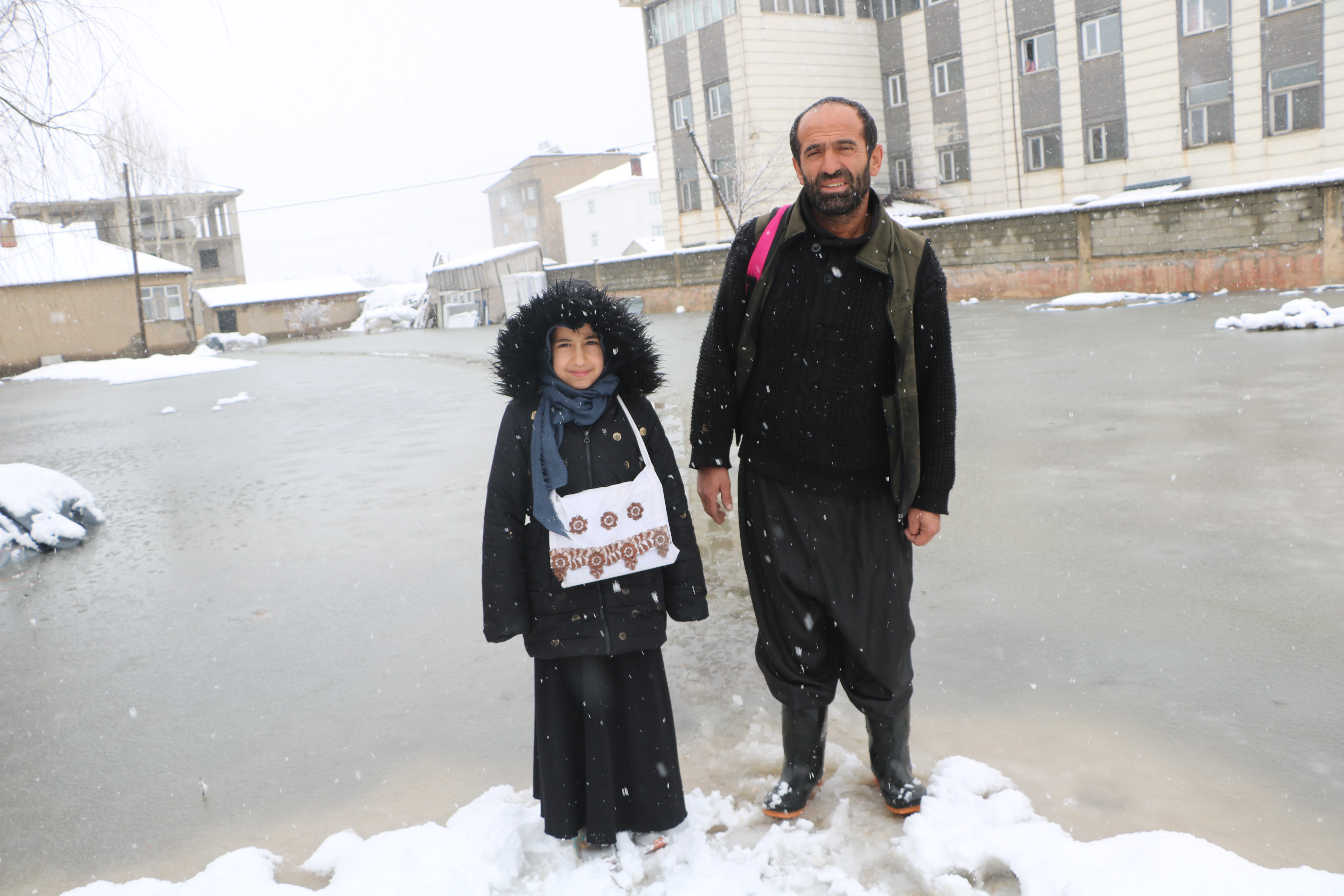 Evinin önünde biriken su nedeniyle çocuklarını sırtında taşıyor